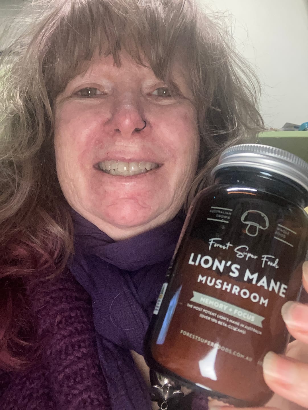 Smiling customer holding Lions Mane Mushroom Capsules by Forest Super Foods