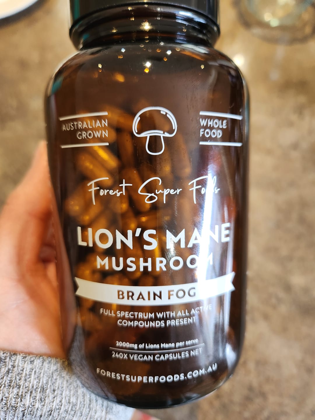 Customer holding Lions Mane Mushroom Capsules and describing feeling clearer and more focused since using them daily.